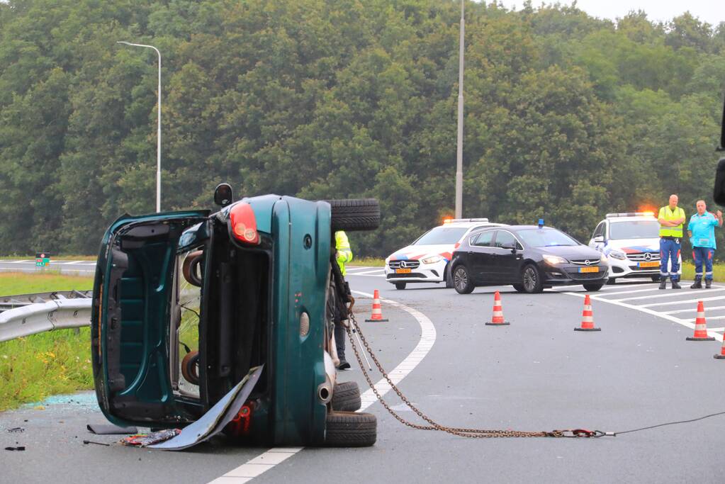 Auto glijdt over vangrail heen en belandt op zijn kop