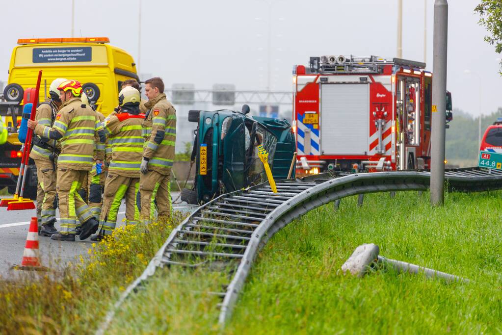 Auto glijdt over vangrail heen en belandt op zijn kop