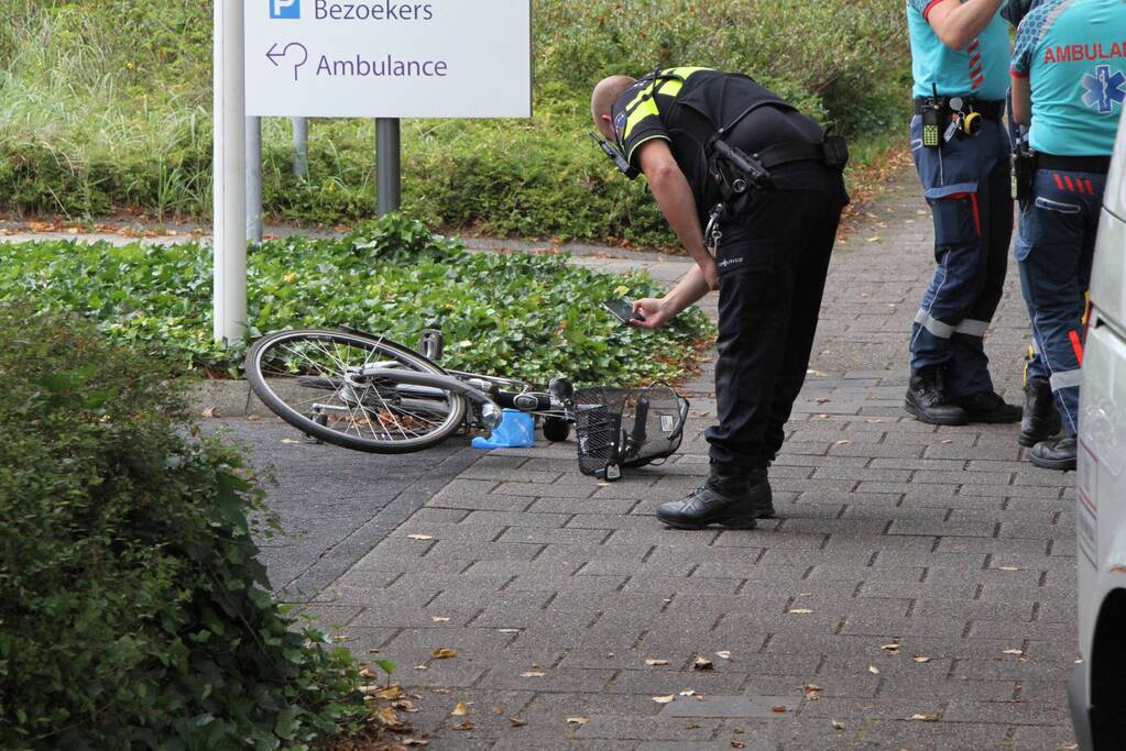 Vrouw met fiets gaat onderuit voor ingang ziekenhuis
