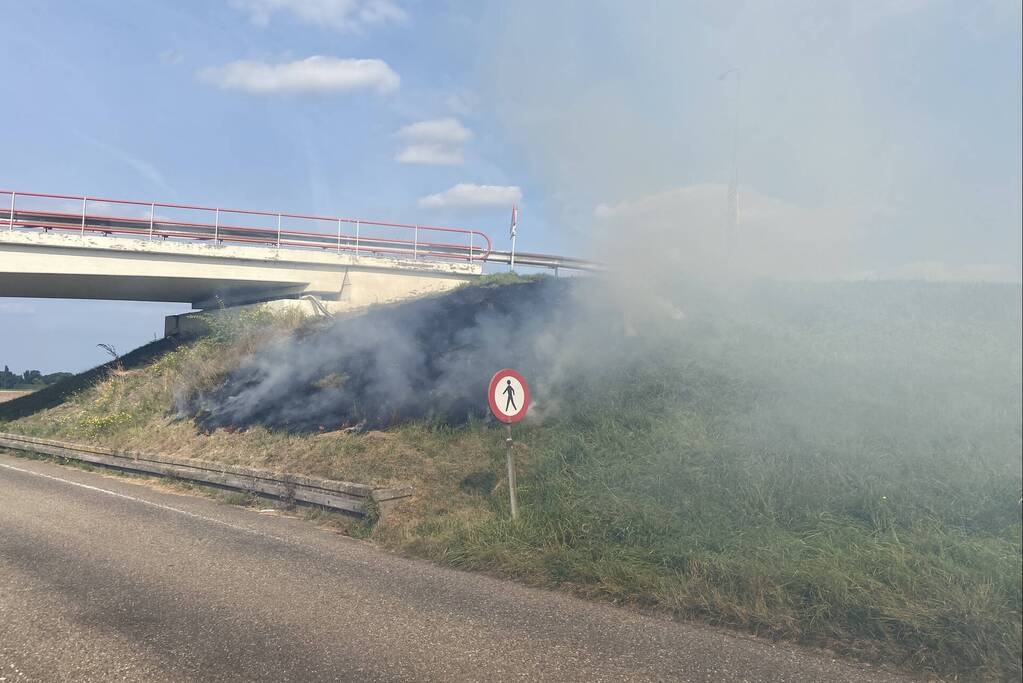 Berm talud naast snelweg vat vlam
