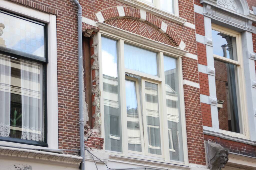 Vrachtwagen met kraan rijdt stuk gevel eruit