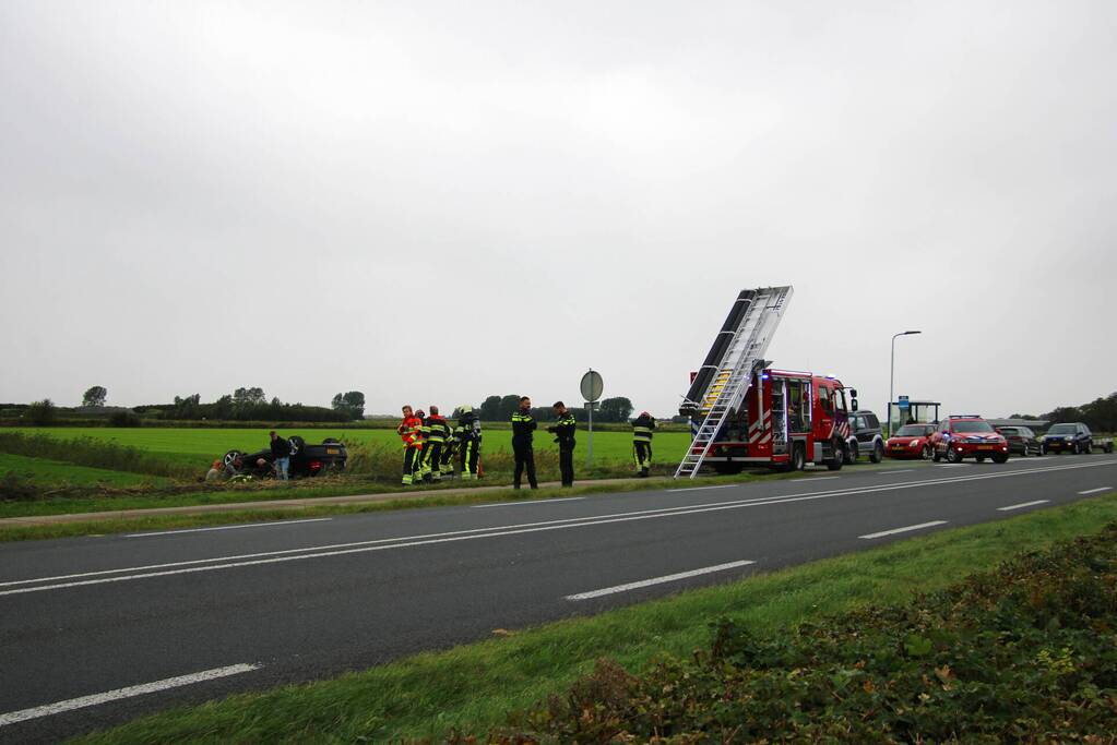 Auto raakt na botsing van de weg en belandt op de kop in weiland