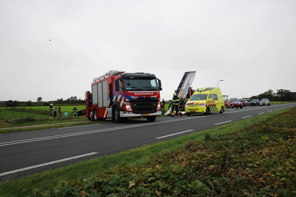 Auto raakt na botsing van de weg en belandt op de kop in weiland