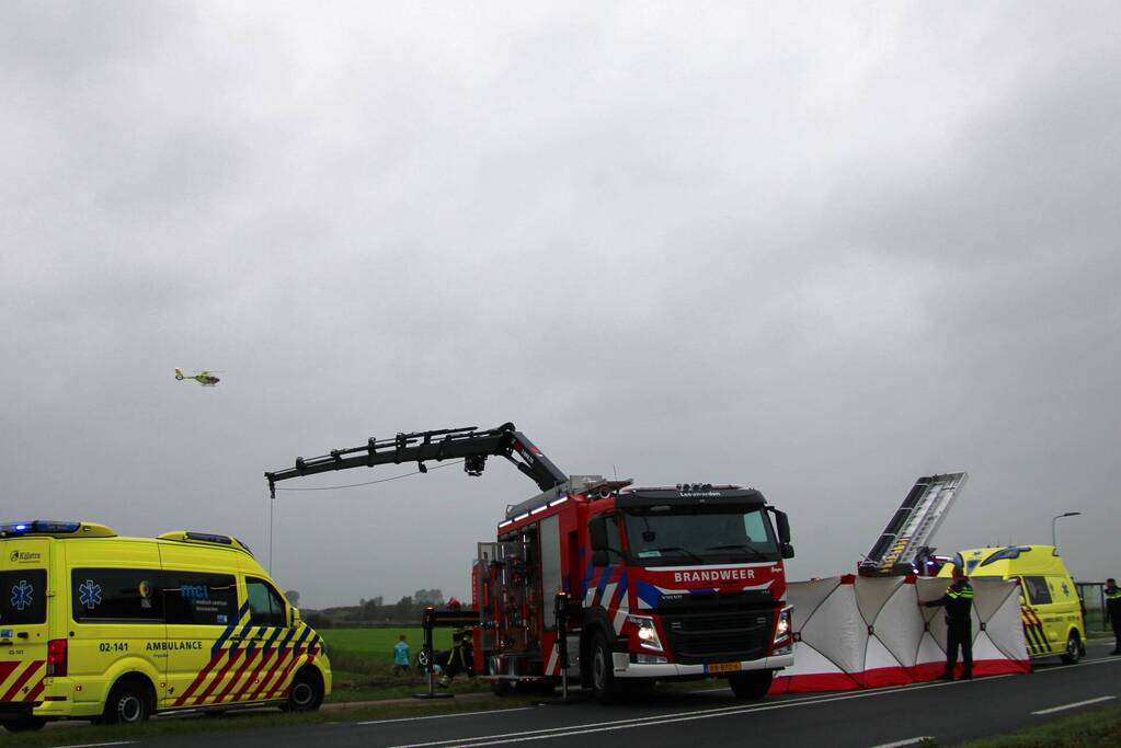 Auto raakt na botsing van de weg en belandt op de kop in weiland