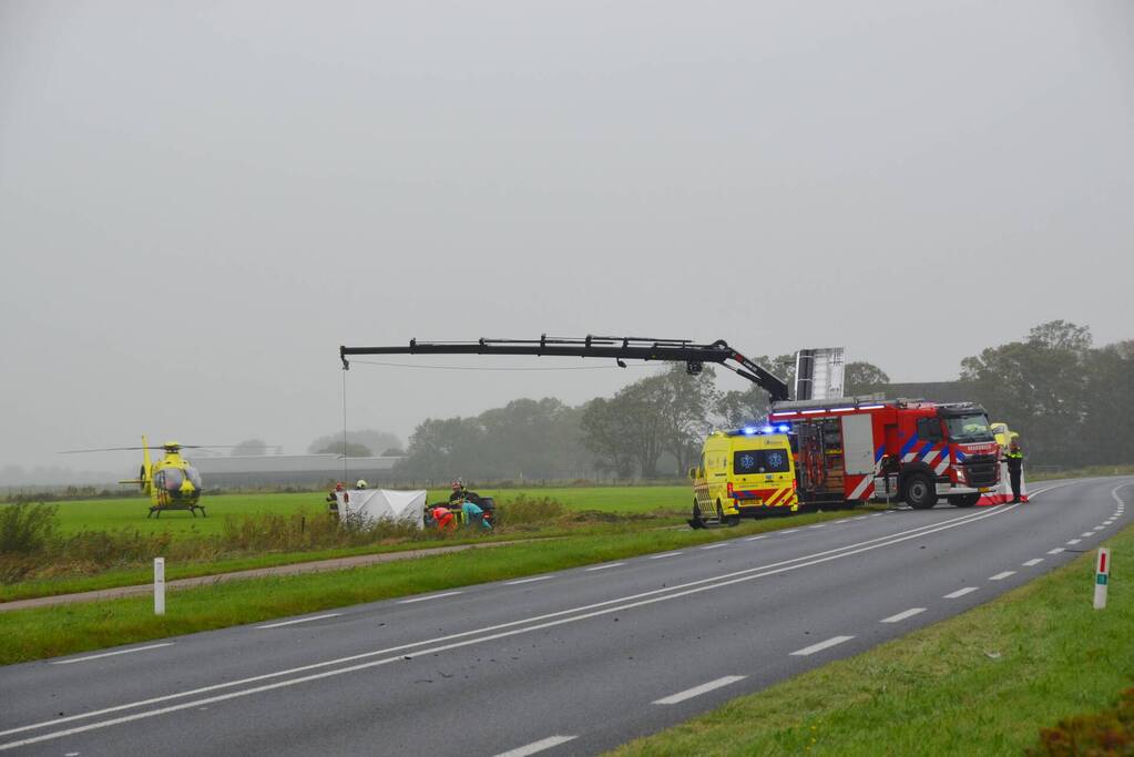 Auto raakt na botsing van de weg en belandt op de kop in weiland