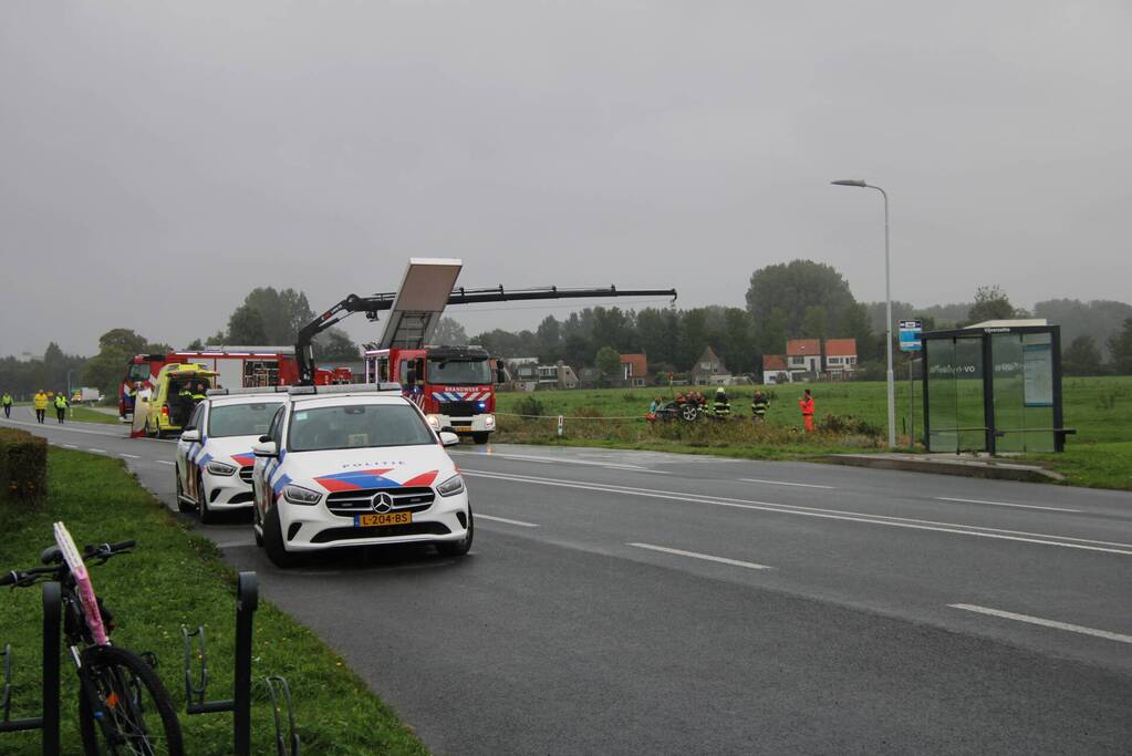 Auto raakt na botsing van de weg en belandt op de kop in weiland