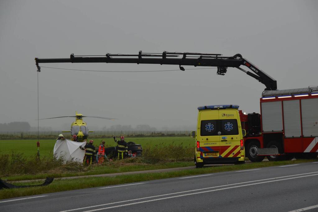 Auto raakt na botsing van de weg en belandt op de kop in weiland