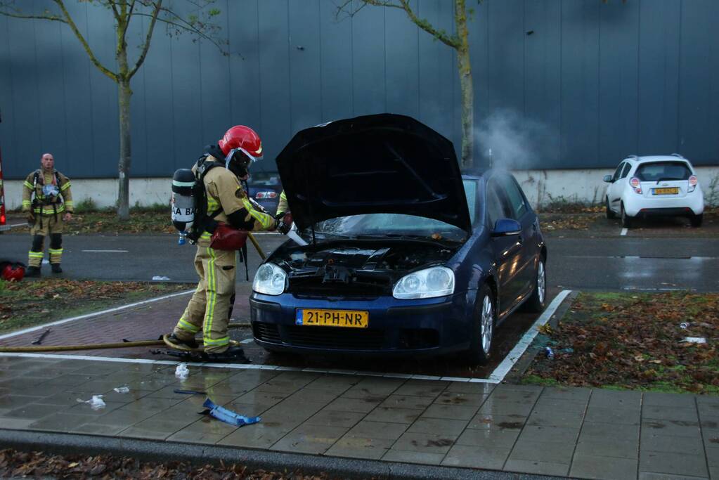 Brandweer blust brand in geparkeerde auto