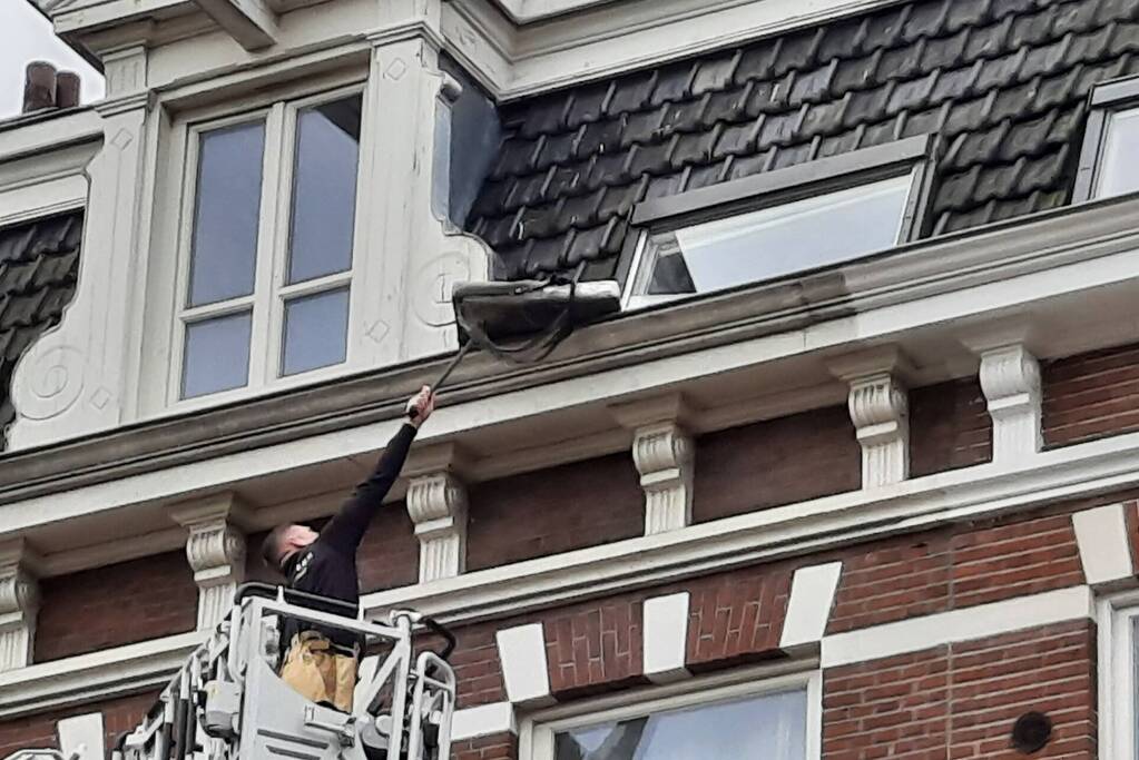 Brandweer haalt kussen uit dakgoot