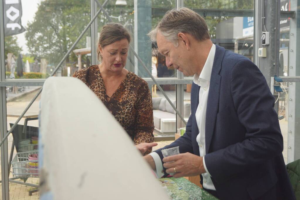 Burgemeester Röell helpt bij beplakken Social Sofa bij woonwarenhuis Nijhof