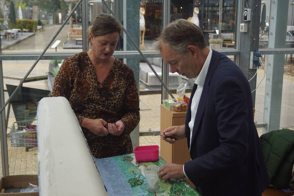Burgemeester Röell helpt bij beplakken Social Sofa bij woonwarenhuis Nijhof