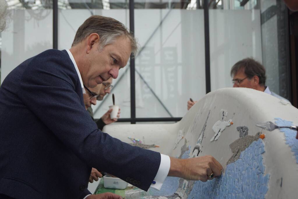 Burgemeester Röell helpt bij beplakken Social Sofa bij woonwarenhuis Nijhof