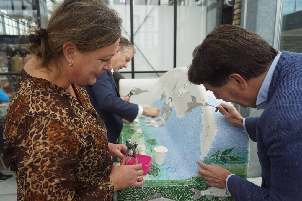 Burgemeester Röell helpt bij beplakken Social Sofa bij woonwarenhuis Nijhof