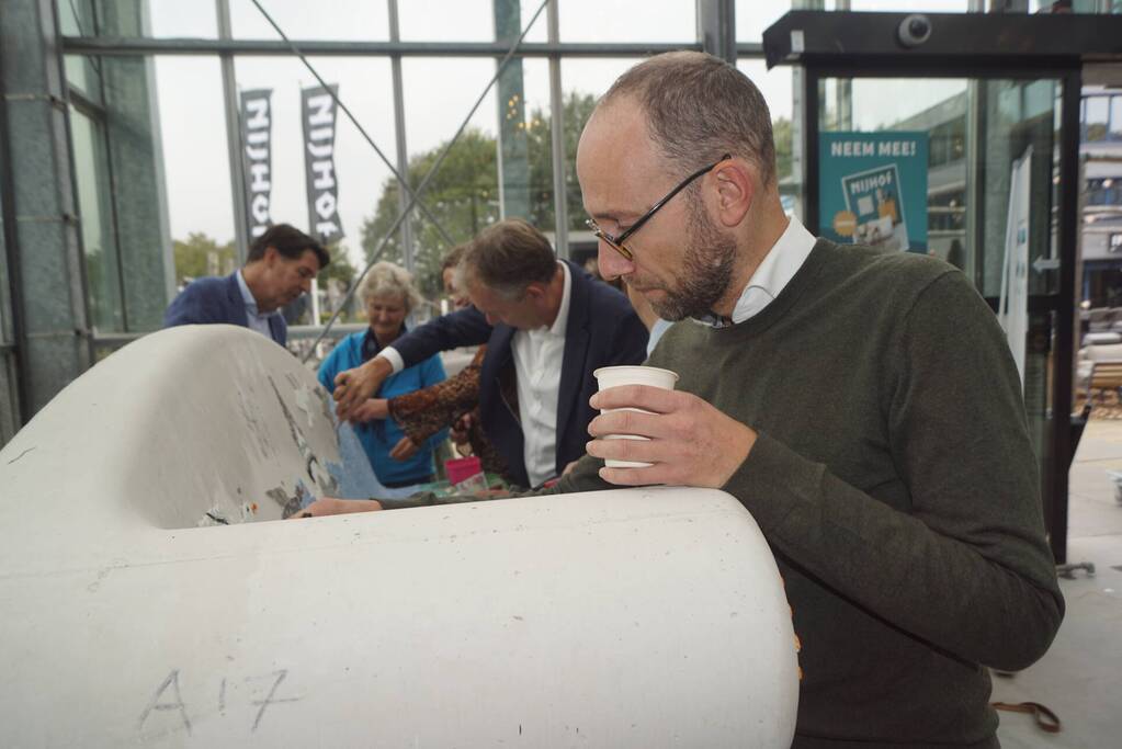 Burgemeester Röell helpt bij beplakken Social Sofa bij woonwarenhuis Nijhof