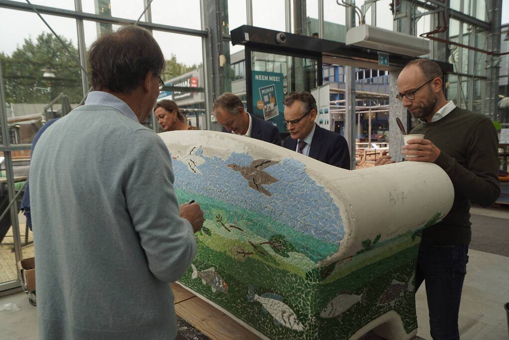 Burgemeester Röell helpt bij beplakken Social Sofa bij woonwarenhuis Nijhof