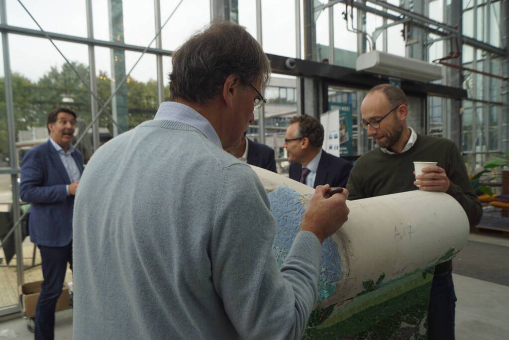 Burgemeester Röell helpt bij beplakken Social Sofa bij woonwarenhuis Nijhof