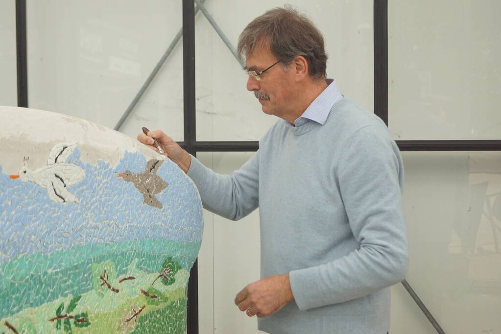 Burgemeester Röell helpt bij beplakken Social Sofa bij woonwarenhuis Nijhof