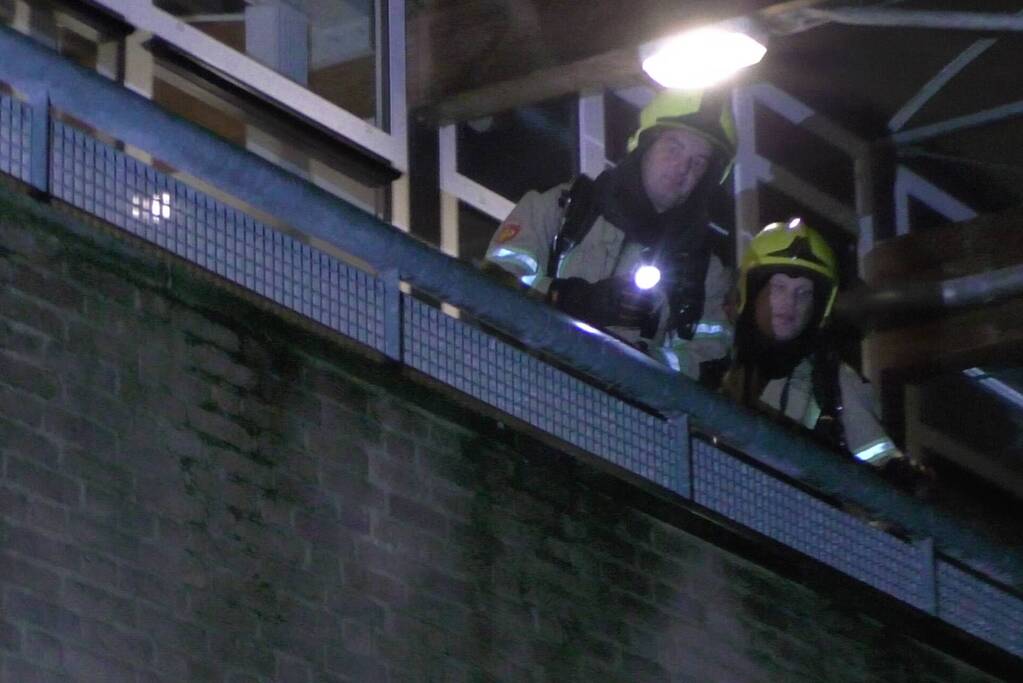 Brandweer blust brandende container tegen school