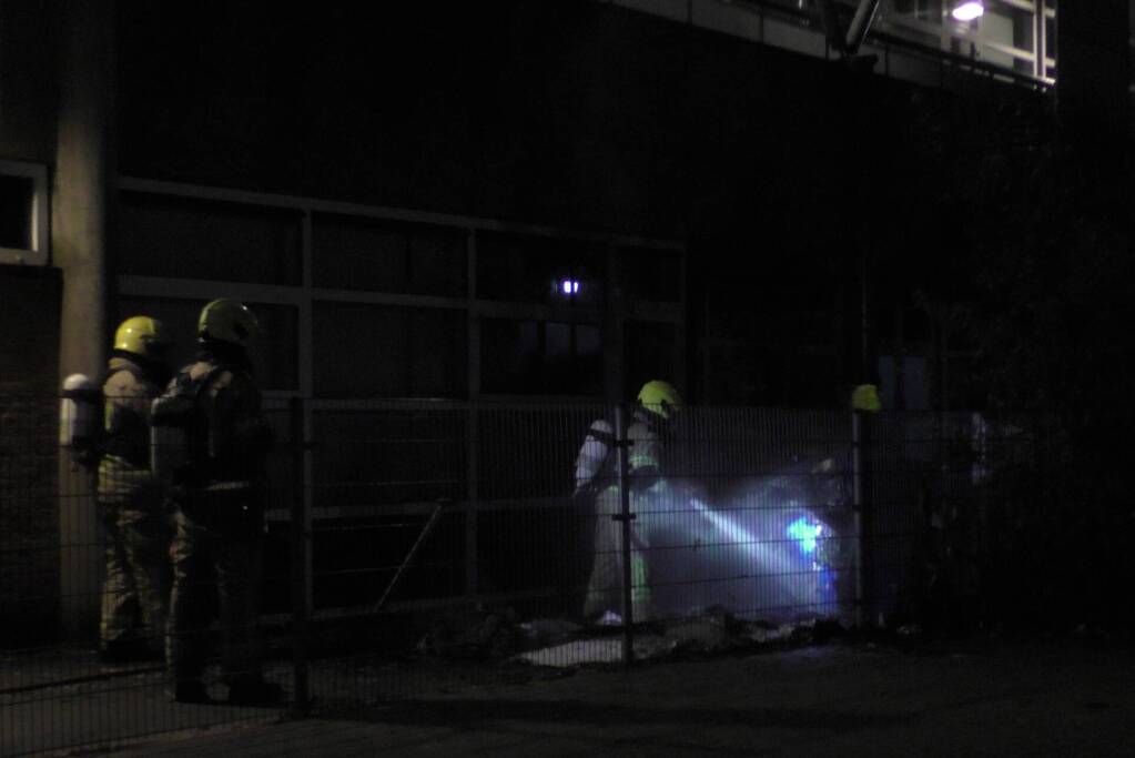Brandweer blust brandende container tegen school