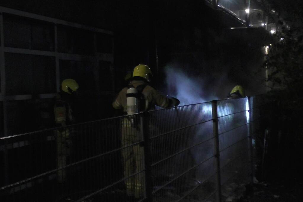 Brandweer blust brandende container tegen school