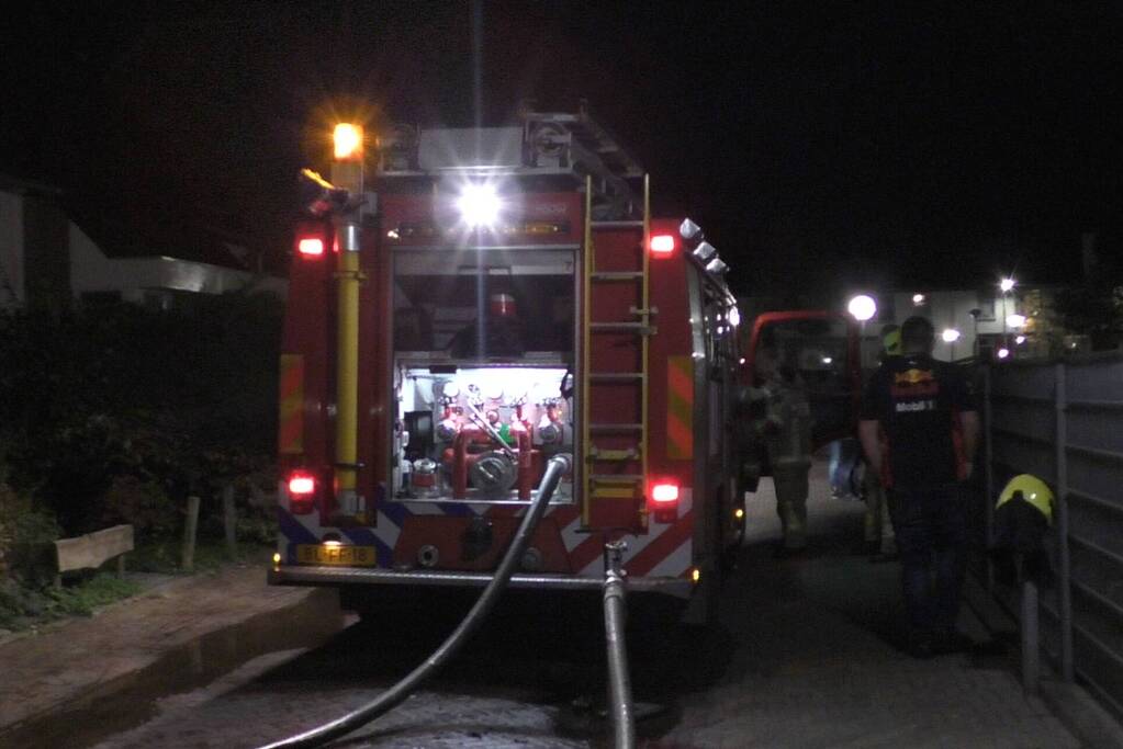 Brandweer blust brandende container tegen school