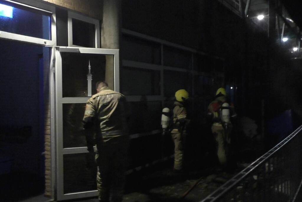 Brandweer blust brandende container tegen school