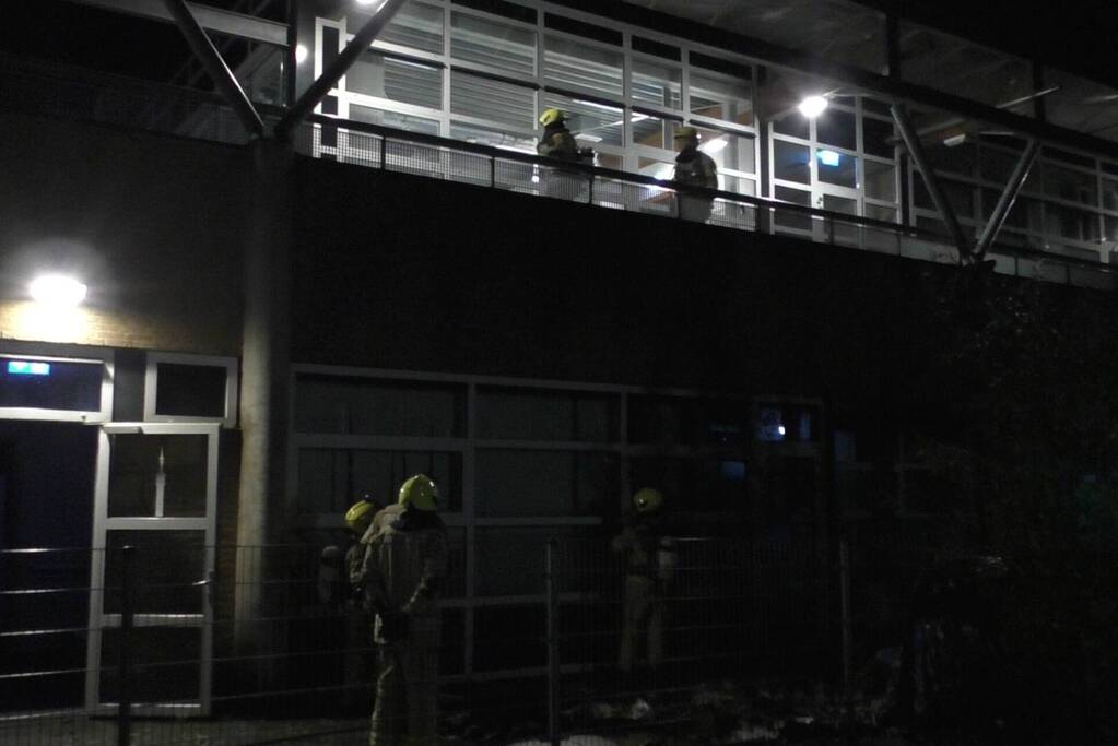 Brandweer blust brandende container tegen school