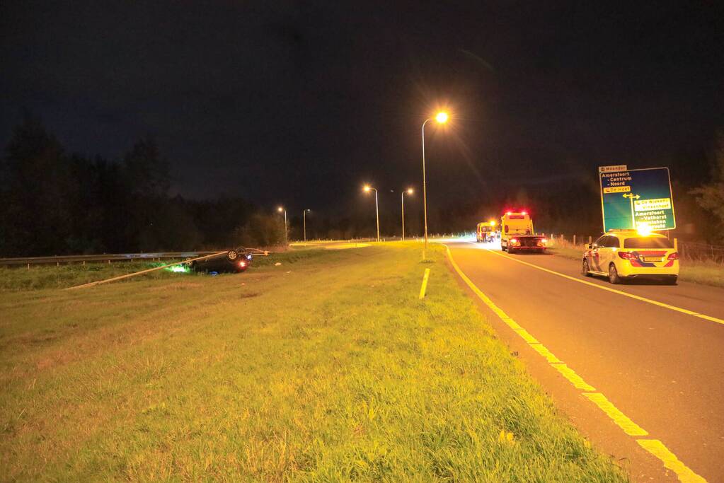 Auto belandt op z'n kop naast snelweg