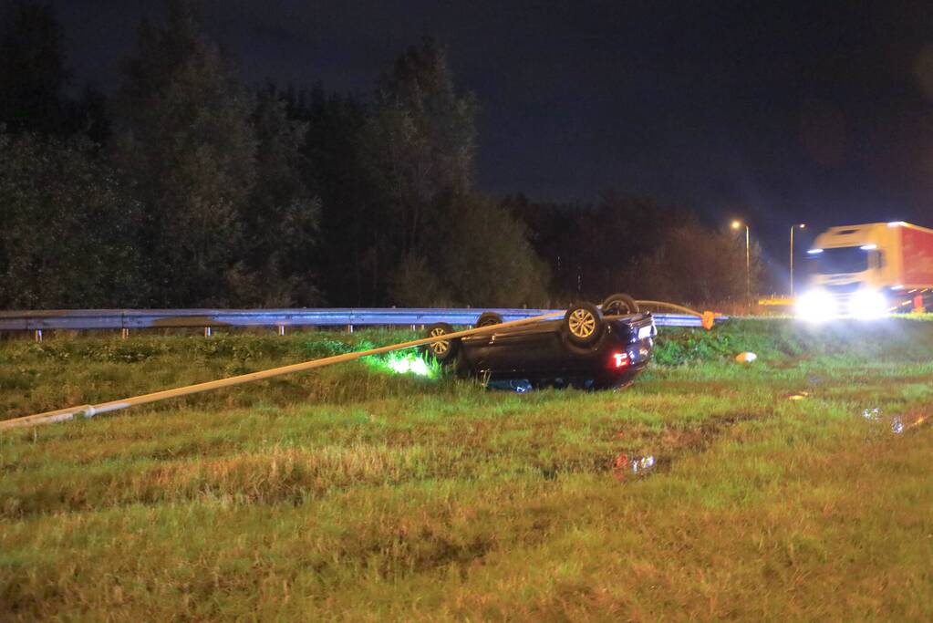 Auto belandt op z'n kop naast snelweg