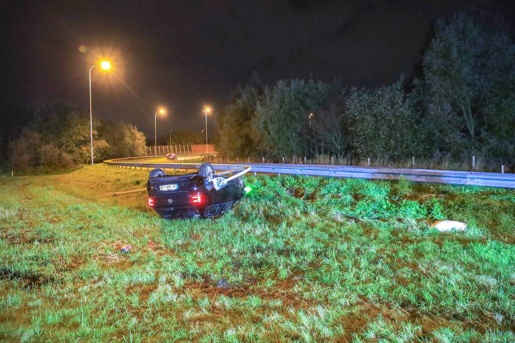 Auto belandt op z'n kop naast snelweg