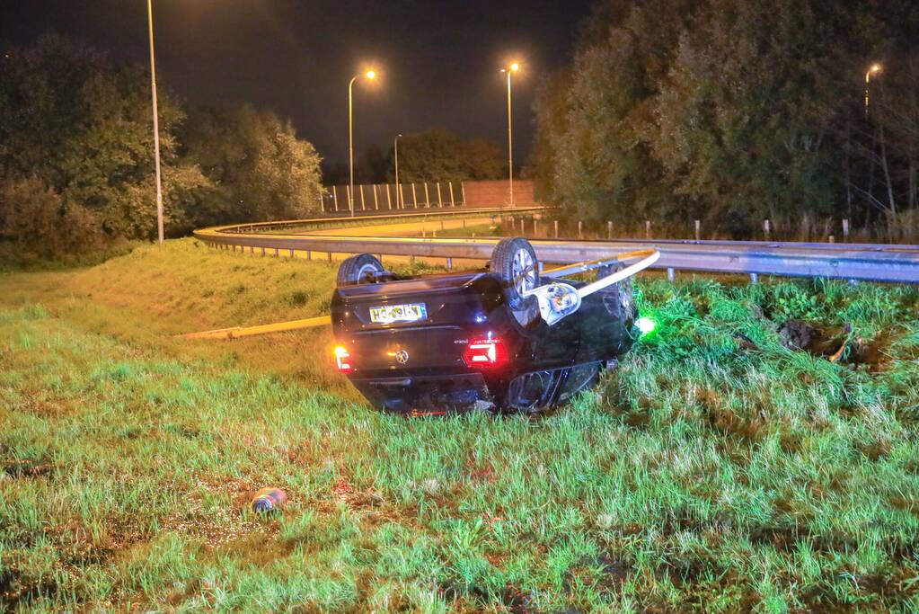 Auto belandt op z'n kop naast snelweg