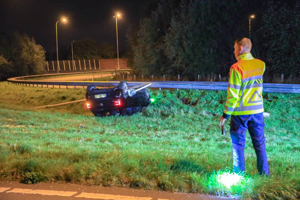 Auto belandt op z'n kop naast snelweg