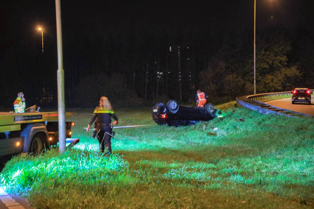Auto belandt op z'n kop naast snelweg