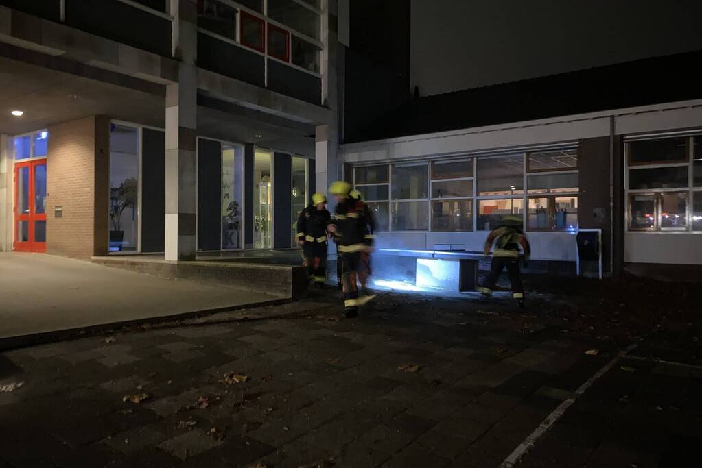 Brandweer blust brandende hoop kranten op schoolplein