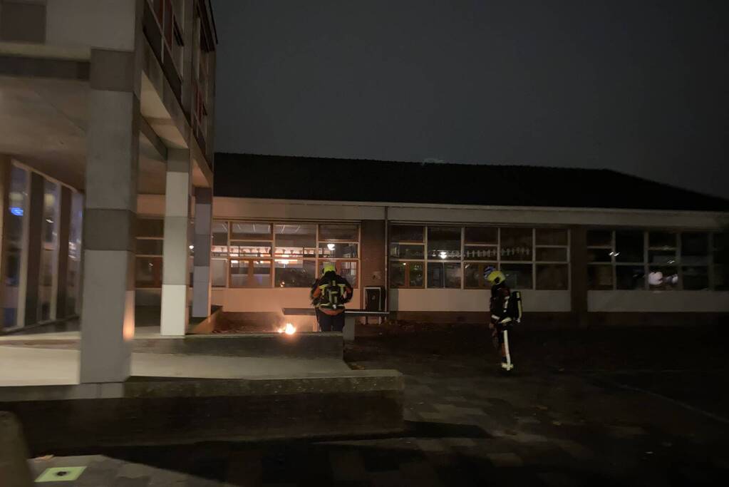 Brandweer blust brandende hoop kranten op schoolplein