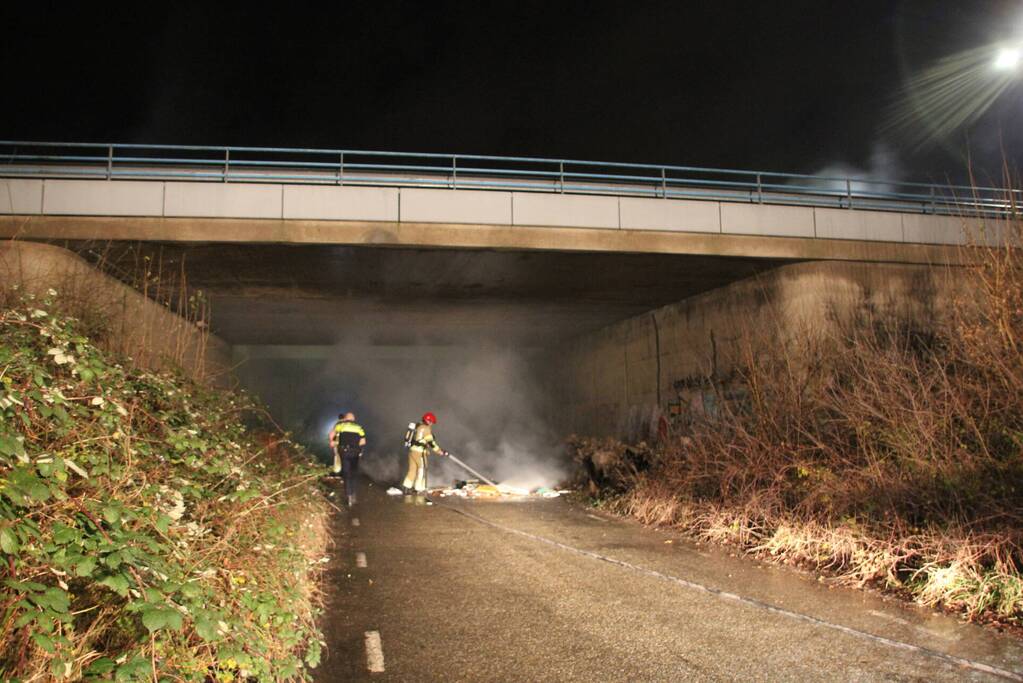 Stapel afval in brand onder brug over snelweg