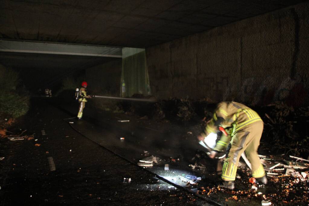 Stapel afval in brand onder brug over snelweg