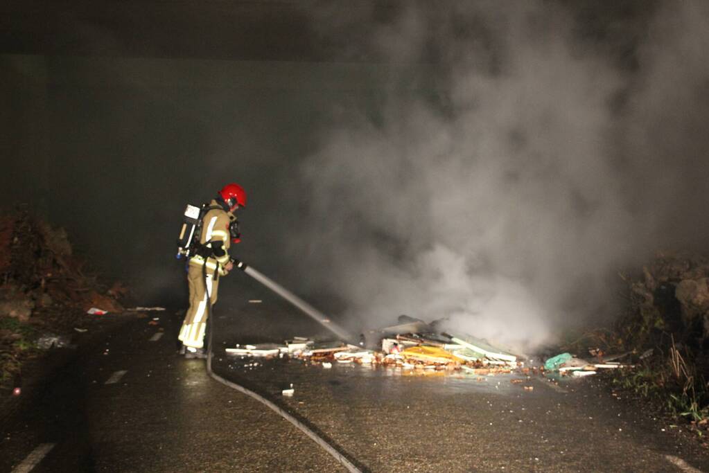 Stapel afval in brand onder brug over snelweg