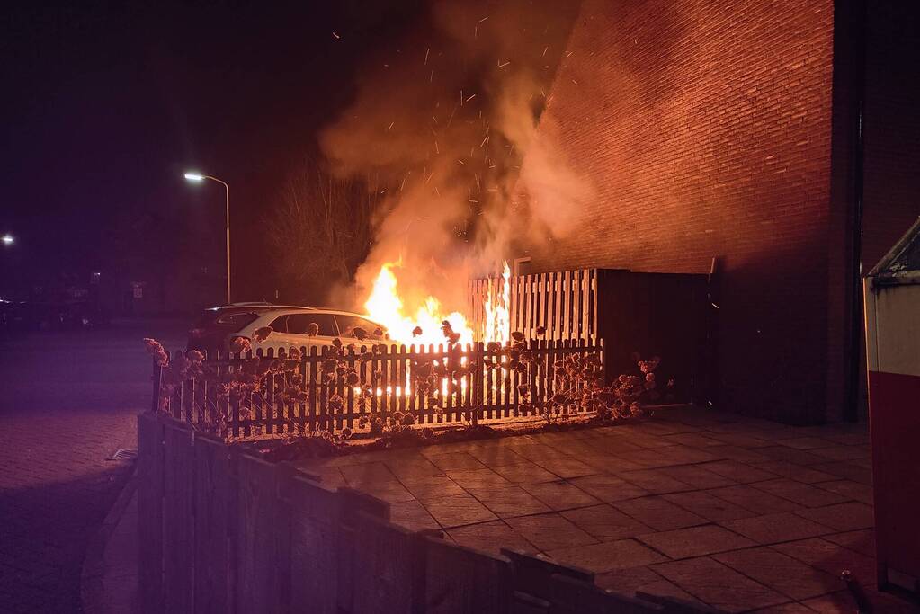 Auto en schutting in brand