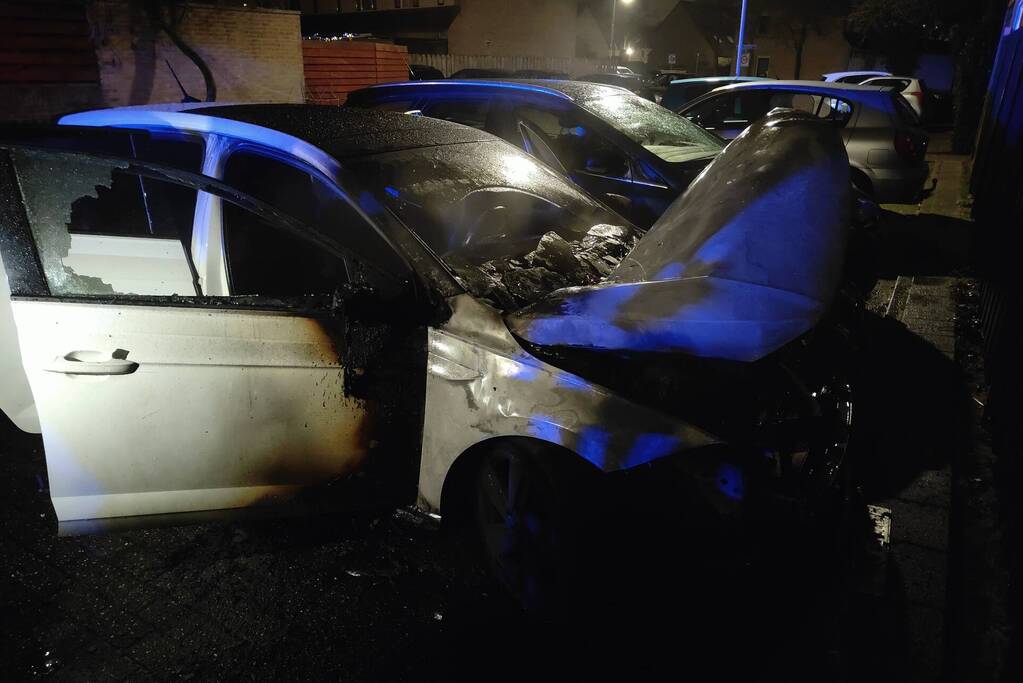 Auto en schutting in brand