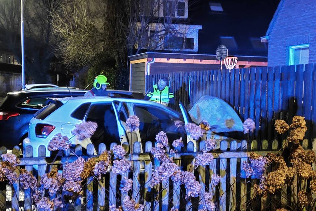 Auto en schutting in brand