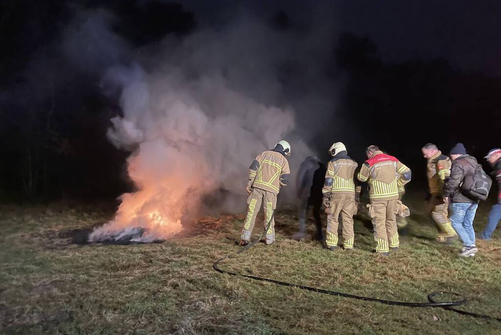 Brandweer blust brandende hoop afval