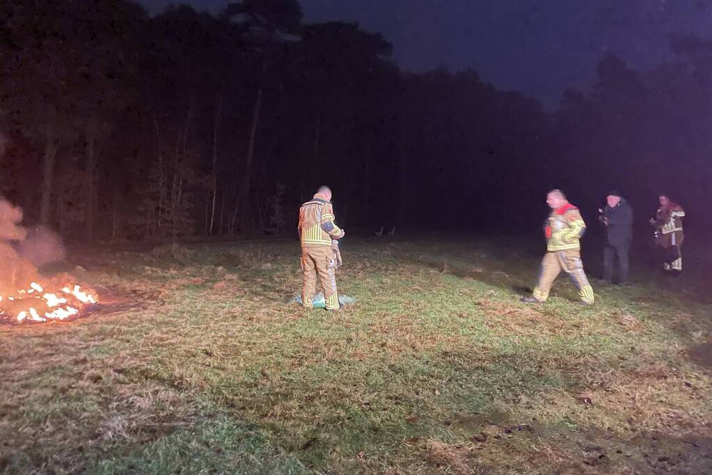 Brandweer blust brandende hoop afval