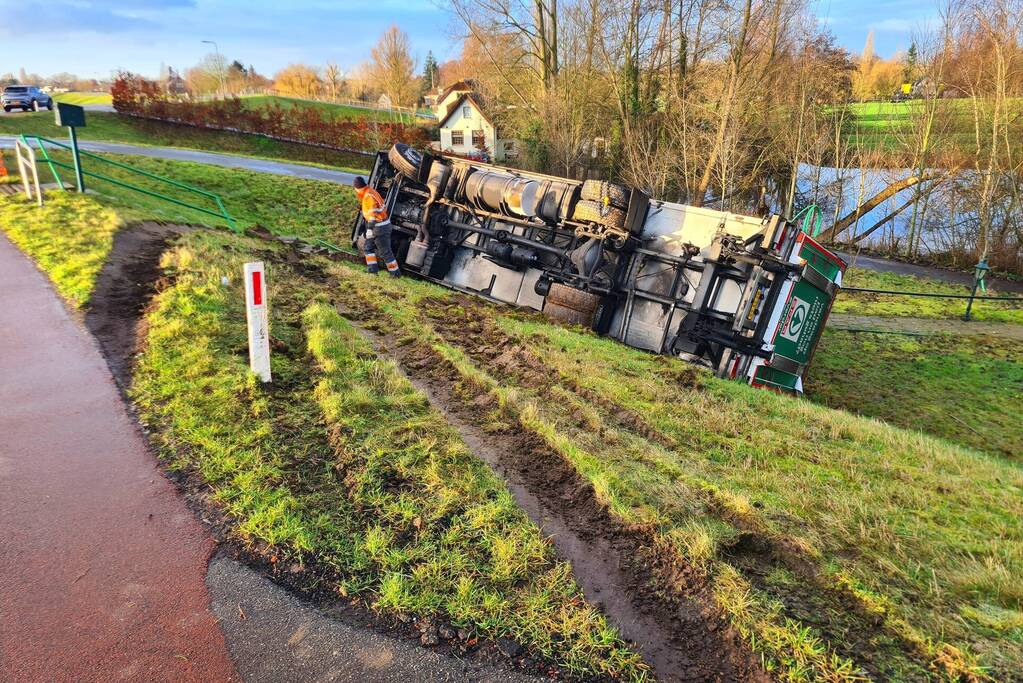Vrachtwagen belandt op zijn kant onderaan dijk