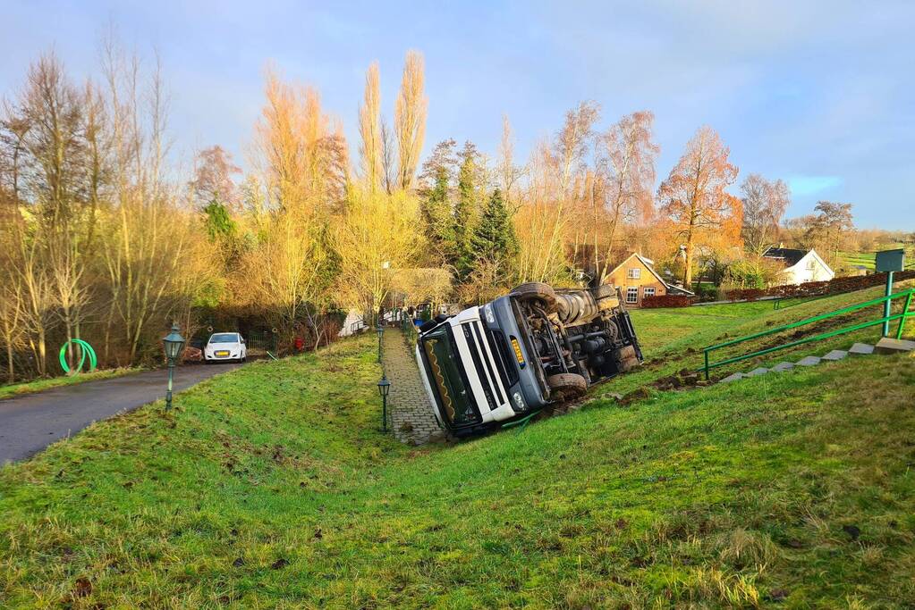 Vrachtwagen belandt op zijn kant onderaan dijk