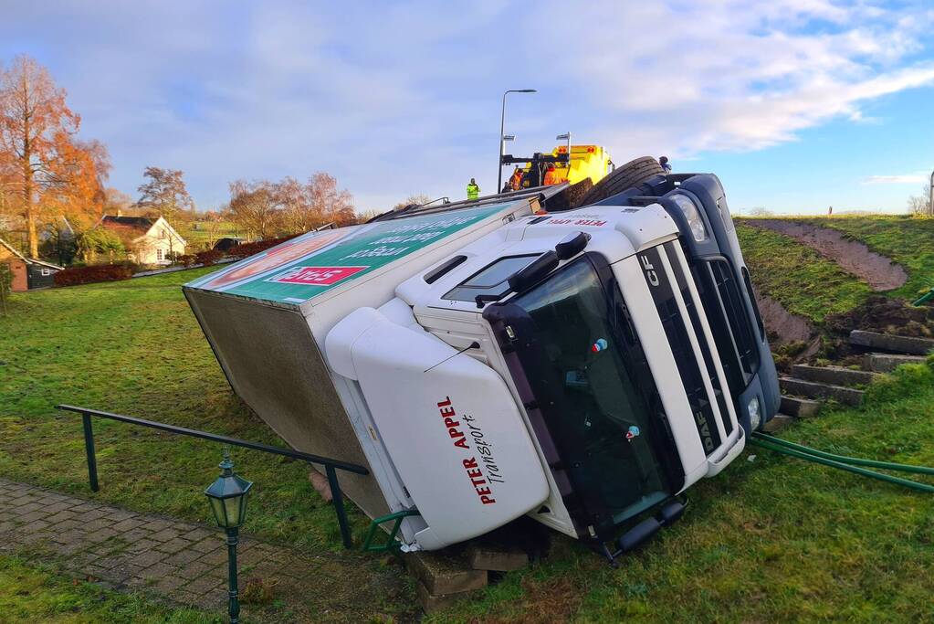 Vrachtwagen belandt op zijn kant onderaan dijk