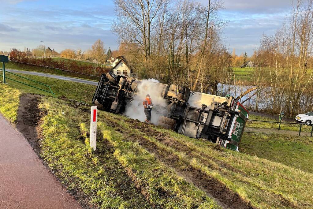 Vrachtwagen belandt op zijn kant onderaan dijk