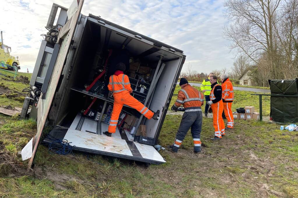 Vrachtwagen belandt op zijn kant onderaan dijk