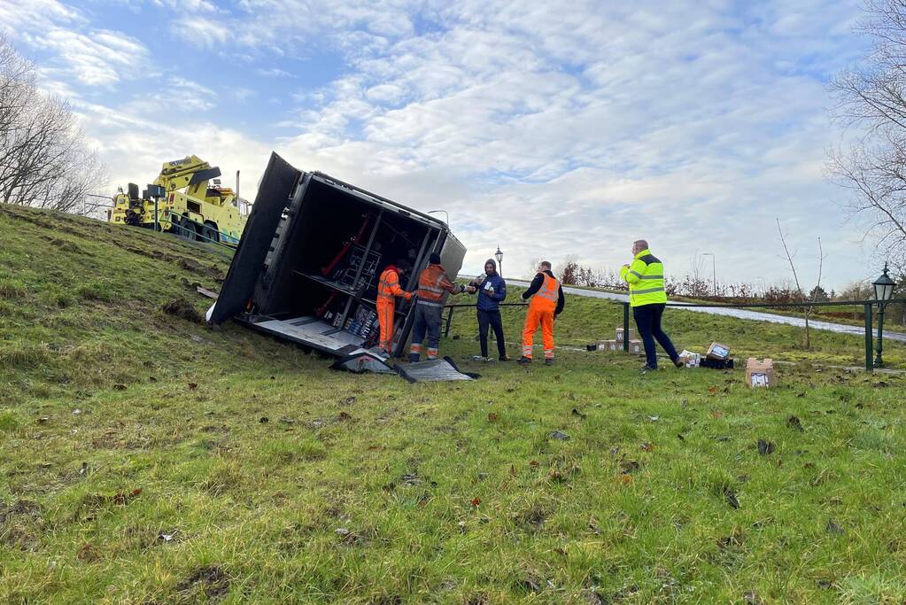 Vrachtwagen belandt op zijn kant onderaan dijk