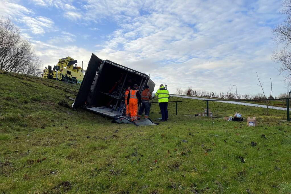 Vrachtwagen belandt op zijn kant onderaan dijk